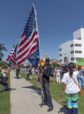 Beverly Hills, CA / USA - 1 Ağustos 2020: Kaliforniya Kongre Adayı Errol Webber özgürlük mitinginde bir Amerikan Bayrağı tutuyor