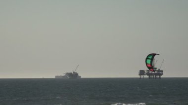 Parasailer Pasifik Okyanusu açıklarında petrol sondaj platformlarından geçiyor.