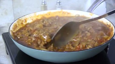 Dökme demir tavada spagetti sosu kaynıyor.