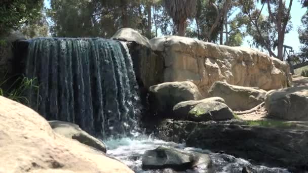 在洛杉矶肯尼斯 哈恩公园的一个美丽瀑布后 人们看到一个石油桶在夏天的一天里工作 — 图库视频影像
