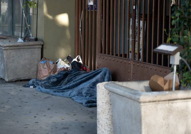 Los Angeles, CA USA - 9 Ocak 2021: Öndeki kaldırımda uyuyan evsiz bir adam veya Coronavirus karantinası tarafından kapatılmış bir restoran