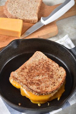 Dökme demir tavada malzemelerle ızgara peynirli sandviç.