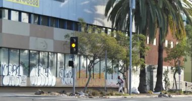 Los Angeles, CA USA - 29 Aralık 2020: Evsiz bir adam boş, hasarlı duvar yazısıyla kaplı bir binanın yanından geçiyor