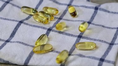 Balık yağı ya da Omega 3 yağ kapsülleri mutfak havlusuna düşüyor.