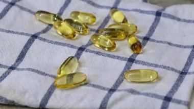 Balık yağı ya da Omega 3 yağ kapsülleri mutfak havlusuna düşüyor. 