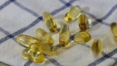 Balık yağı ya da Omega 3 yağ kapsülleri mutfak havlusuna düşüyor.