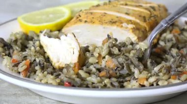 Çatal dolusu yaban pirinci ve biberiyeli tavuk yemek.