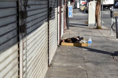 Los Angeles, CA USA - 13 Mayıs 2021: Los Angeles şehir merkezinde kaldırımda uyuyan evsiz bir kadın