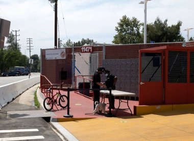 Kuzey Hollywood, CA USA - 28 Mayıs 2021: Güvenlik görevlisi Chandler Tiny Home Village 'da yaşayan evsiz insanları kontrol ediyor