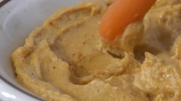 Окунуть Морковку Тарелку Свежего Хумуса — стоковое видео