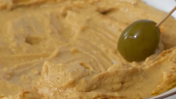 Eine Grüne Olive Eine Schüssel Mit Humus Tauchen Nahaufnahme Zeitlupe — Stockvideo