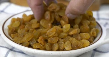 Bir kâseden bir avuç taze altın kuru üzüm alıyorum.