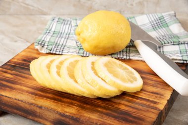 Kesme tahtasındaki dilimlenmiş limon ve mutfak bıçağı.