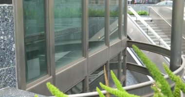 Dışarıdaki yürüyen merdivenin yanında cam bir asansör var.