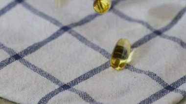 Balık yağı ya da Omega 3 yağ kapsülleri çok yavaş çekimde peçeteye düşüyor.