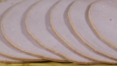 Tahta bir kesme tahtasının üzerinde dilimlenmiş salam boyunca kaygan bir atış.