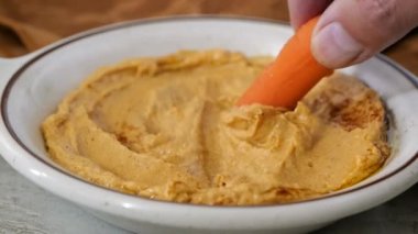 Bebek havucu taze ev yapımı humus kasesine batırmak süper ağır çekim.