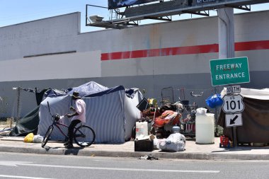 Los Angeles, CA USA - 30 Haziran 2021 Los Angeles 'taki Hollywood Otoyolu' nun girişindeki bir kampta bisikletli evsiz adam