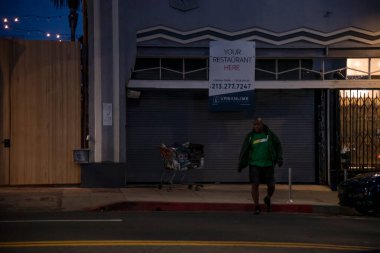Los Angeles, CA USA - 4 Mayıs 2021: Tecritten sonra tekrar açılamayan bir restoranın önündeki evsiz kişi