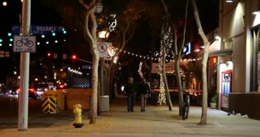 Batı Hollywood, CA USA - 9 Aralık 2020: WeHo 'da Noel karantinası sırasında kaldırım kafeleri boyunca yürüyen iki kişi