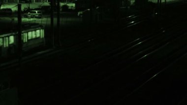 Gece yeşil gece görüşlü iki tren tren tren istasyonundan geçiyor.