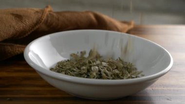 Kurutulmuş maydanoz taneleri küçük bir tabağın içine düşüyor.