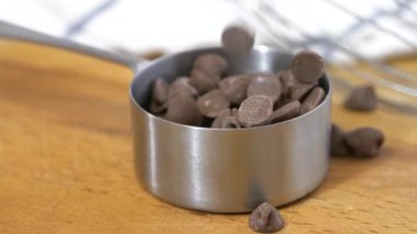 Sütlü çikolata parçalarını paslanmaz çelikten bir bardağa dolduruyorlar. Süper yavaş çekim.