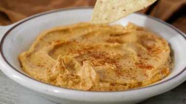 Mısırlı tortilla cipsini bir kase humusa batırıyorum.