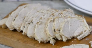 Tahta kesme tahtasından dilimlenmiş tavuk göğsünü çıkarıyorum.