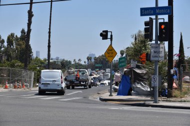 Los Angeles, CA USA - 30 Haziran 2021: Trafik rampadan geçen bir evsizler kampının yanından geçiyor