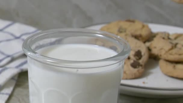 チョコレートチップクッキーをミルクのガラスにぶつけるスローモーション — ストック動画