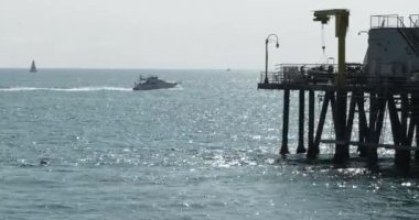 Sürat teknesi ve yelkenli Pasifik Okyanusu 'ndaki Santa Monica iskelesinden geçiyor.