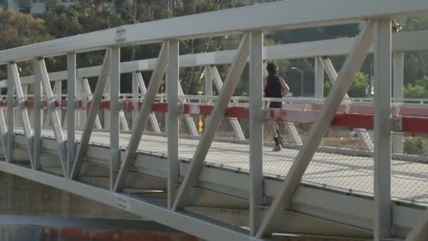 Egy Kocogó Egy Gyalogos Gyalogos Hídon Folyó Felett — Stock videók