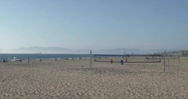 Voleybol ağları ve Kaliforniya 'daki Hermosa Plajı' nda gökkuşağı rengine boyanmış bir cankurtaran kulübesi.