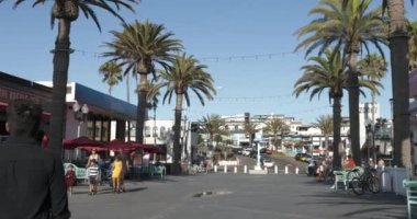 Hermosa Beach, CA USA - 12 Eylül 2021: Hermosa Sahili 'ndeki rıhtımın ağzındaki dükkan ve avluda eğlenen turistler 