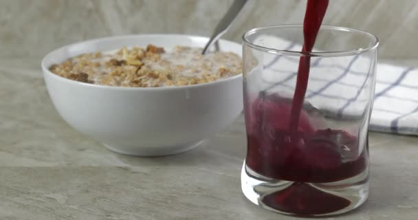 Giet Verse Cranberrysap Een Glas Door Een Kom Granola — Stockvideo