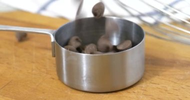 Çikolata parçalarını paslanmaz çelik ölçü kabına döküyorum.