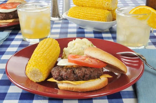 Cheeseburger with corn on the cob — Stock Photo, Image