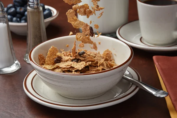 Pouring bran flakes in bowl — Stock Photo, Image