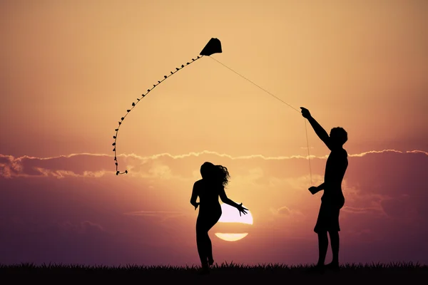 Homem e menina com pipa ao pôr do sol — Fotografia de Stock