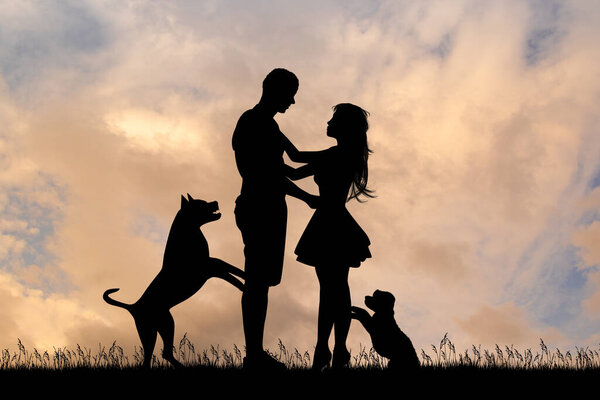 silhouette of couple with dogs at sunset