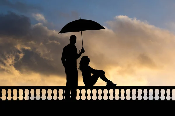 日落时带着雨伞的女孩和男孩的轮廓 — 图库照片