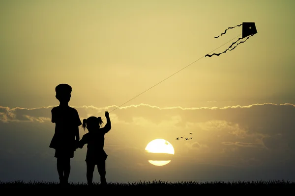 Дети с воздушным змеем на закате — стоковое фото