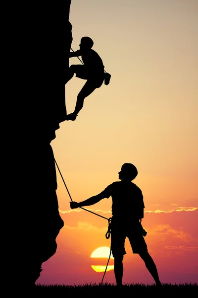 Man climbs mountain at sunset — Stock Photo, Image