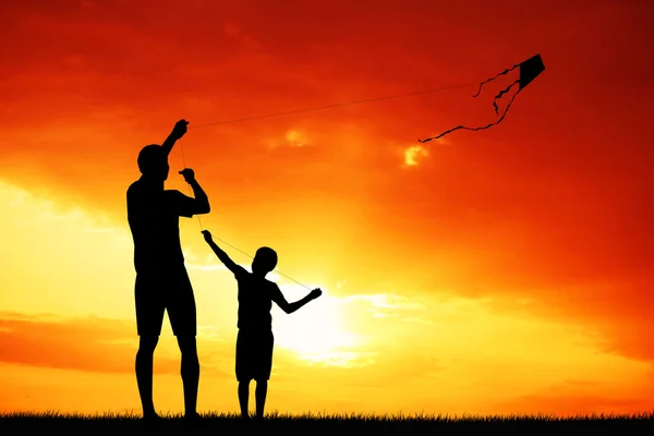 Father and son with kite at sunset — Stock Photo, Image