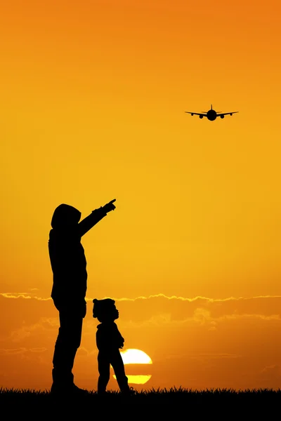 Отец и сын смотрят на самолет на закате — стоковое фото