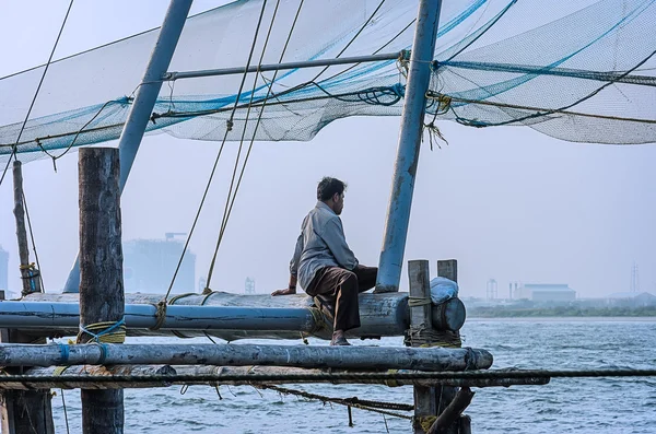 Lonely fisherman sitting on a wooden fishing platform — Stock Photo, Image