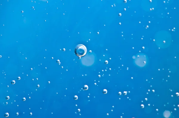 Close-up bubbels onder water op blauwe achtergrond. Macro. — Stockfoto