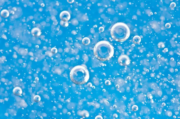 Bolhas brilhantes, movimento sob a água sobre fundo azul . — Fotografia de Stock
