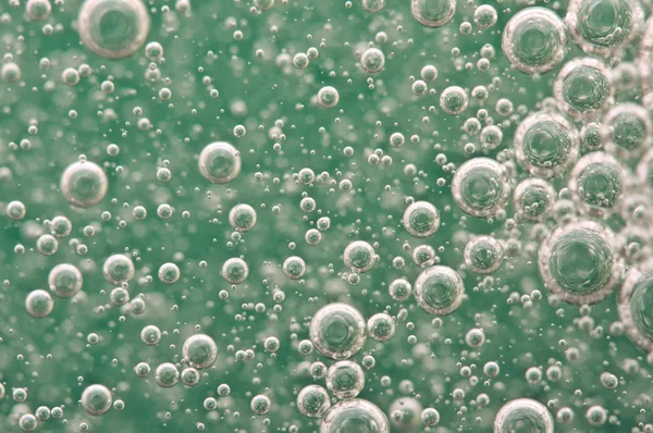 Bulles d'oxygène macro dans l'eau sur un fond vert — Photo